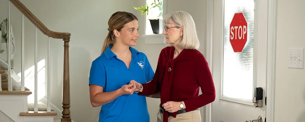 Caregiver assisting an elderly woman inside