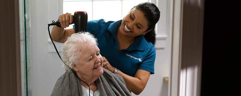 A Visiting Angels caregiver comforting an elderly woman with Alzheimer's, highlighting compassionate support in a peaceful home setting.
