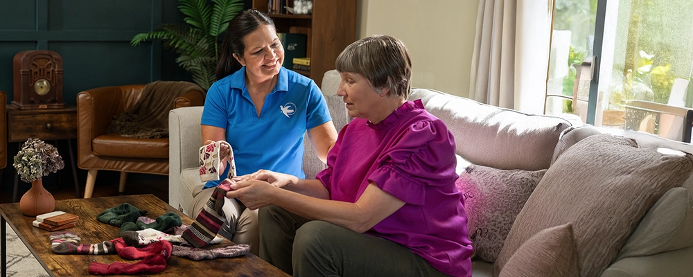 A Visiting Angels caregiver comforting an elderly woman with Alzheimer's, highlighting compassionate support in a peaceful home setting.