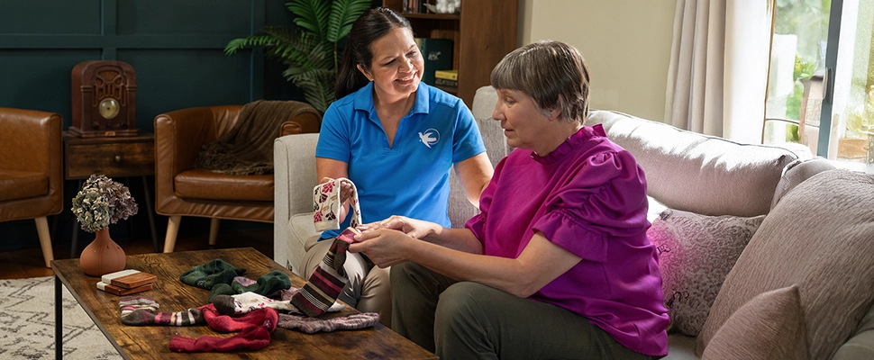 A Visiting Angels caregiver comforting an elderly woman with Alzheimer's, highlighting compassionate support in a peaceful home setting.