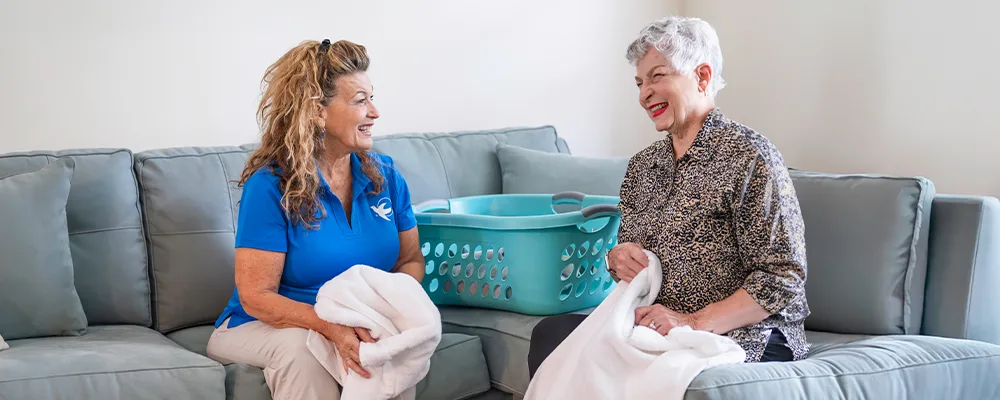 Caregiver assisting elderly woman with laundry