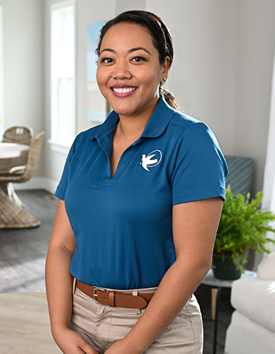 A Visiting Angels caregiver standing and smiling.