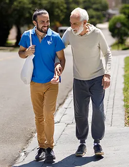 A male Visiting Angels senior home care provider helps an elderly man with his groceries.