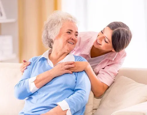 A caregiver smiling with her elderly client.