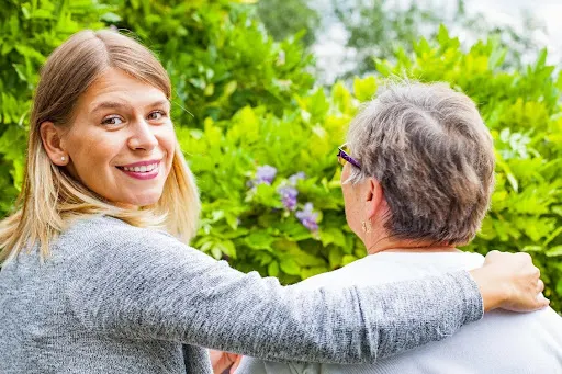 An elderly woman giving her caregiver a high five.