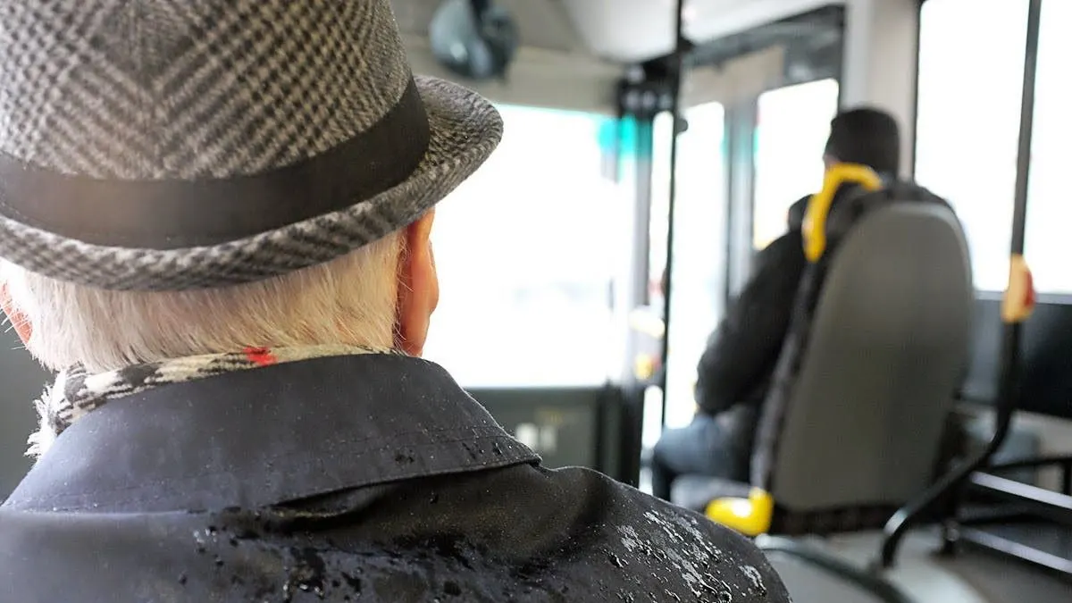An elderly man sitting in a bus.
